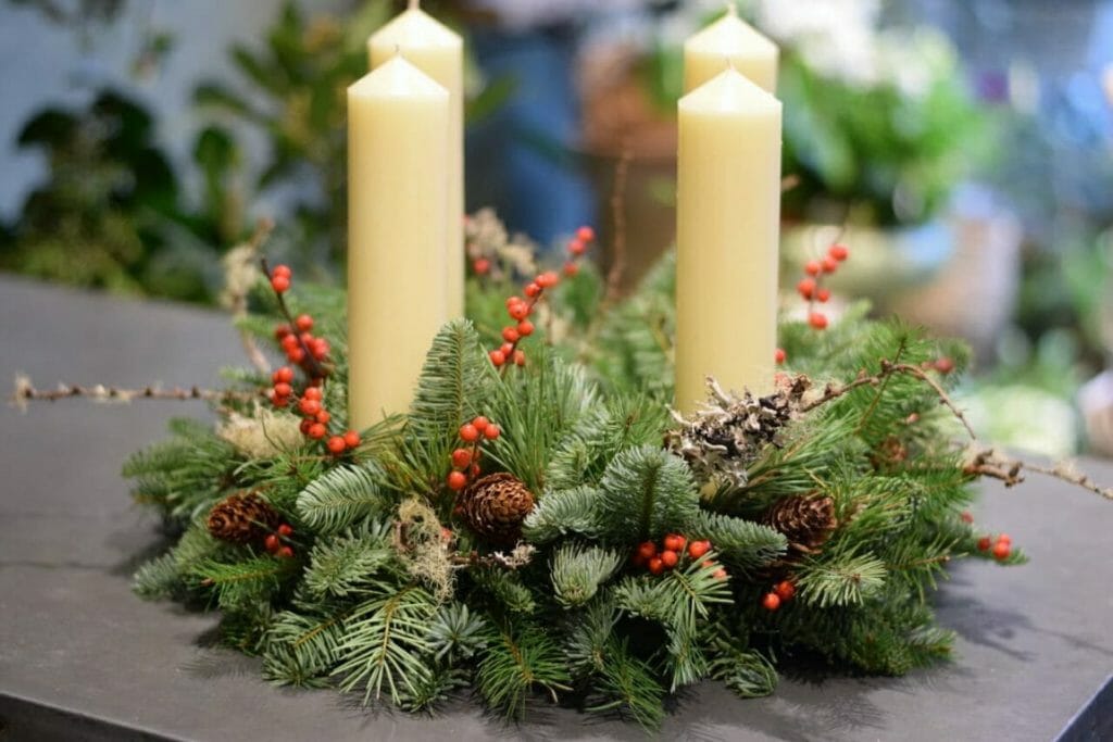 Photo showing a sample of a Christmas Advent candle arrangement mixed rustic foliages, lichen, berry and cones Kensington Flowers London