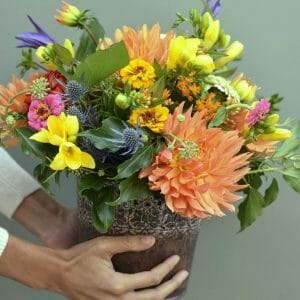 Photo showing a sample bucket of flowers, in orange and yellow colours available for Kensington flowers, London
