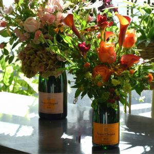 Photo showing a sample image of champagne flower bottle vase arrangements available from Kensington Flowers London