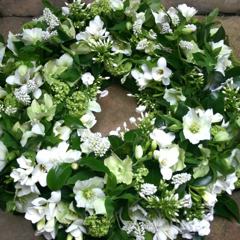 Photo showing a sample of a White funeral wreath spring flowers available at Kensington flowers London