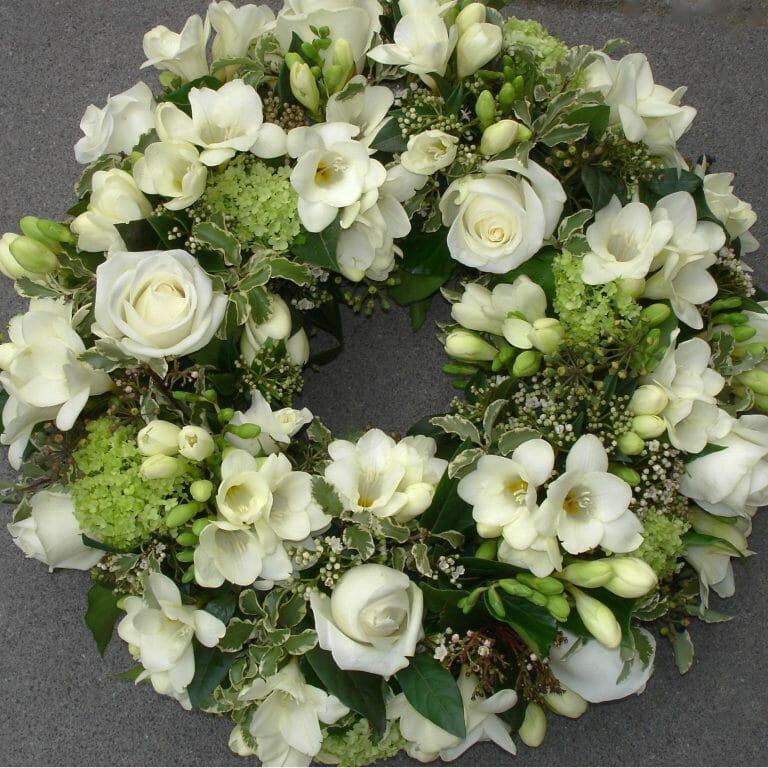 Photo of a White floral wreath funeral tribute of freesia and roses from Kensington flowers London