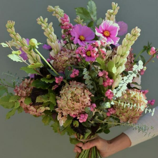 Photo showing a sample of a seasonal hand tied bouquet in dusky pink autumn colours available at Kensington flowers London