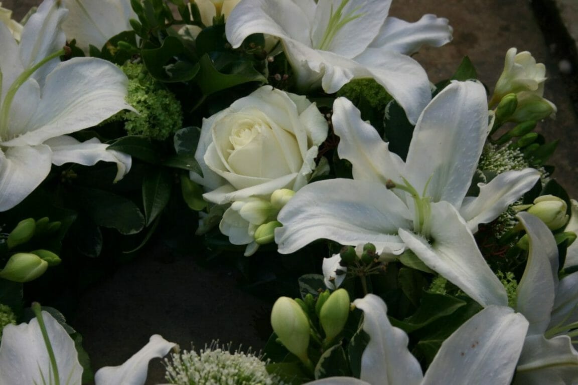 A photo of a close up of an arrangement of Rose and lily funeral flowers