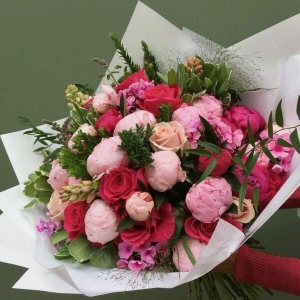 Photograph of a vivid seasonal hand tied bouquet available as a sample of a gift set of Flowers and lemon drizzle cake available to order at Kensington flowers Londonfrom Kensington Flowers London