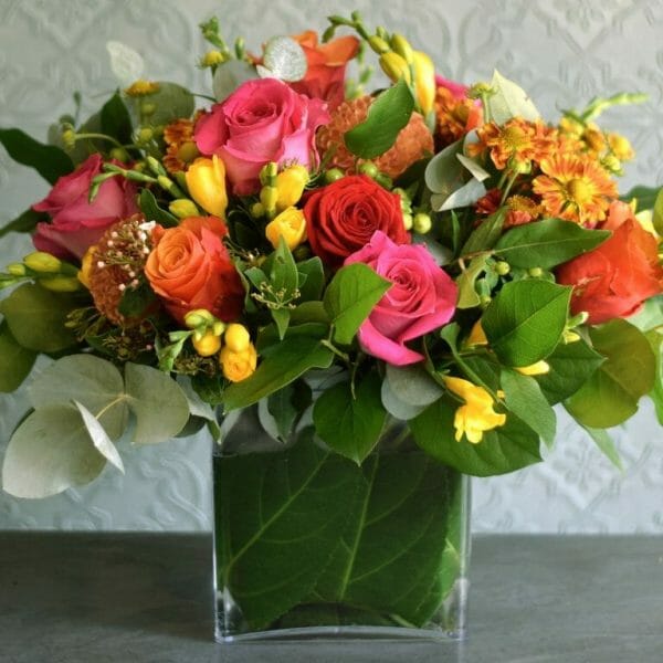 Photo showing a sample image of seasonal vase arrangement mixed vivid colours Kensington flowers