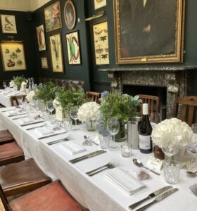Mason jars filled with white hydrangeas or English foliage line tables in a pub 